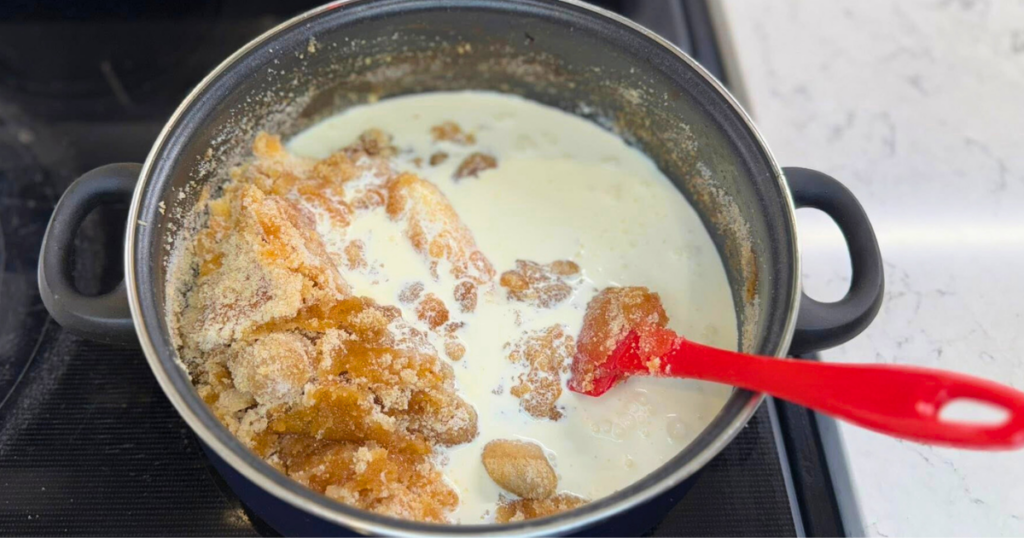 The heavy cream added to the sugars in the large blue pot to make the Homemade Apple Cider Salted Caramel Recipe