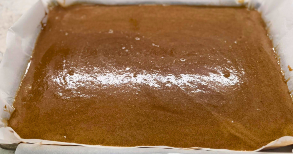 Homemade Apple Cider Salted Caramel Recipe poured into a parchment paper lined baking tray.